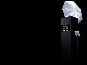 A box photo booth with umbrella lighting on top and ipad